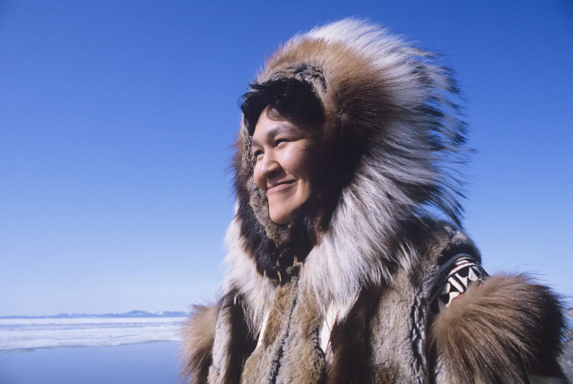 Smiling,Eskimo,Woman,Wearing,Traditional,Clothing,In,Wind,Against,Clear